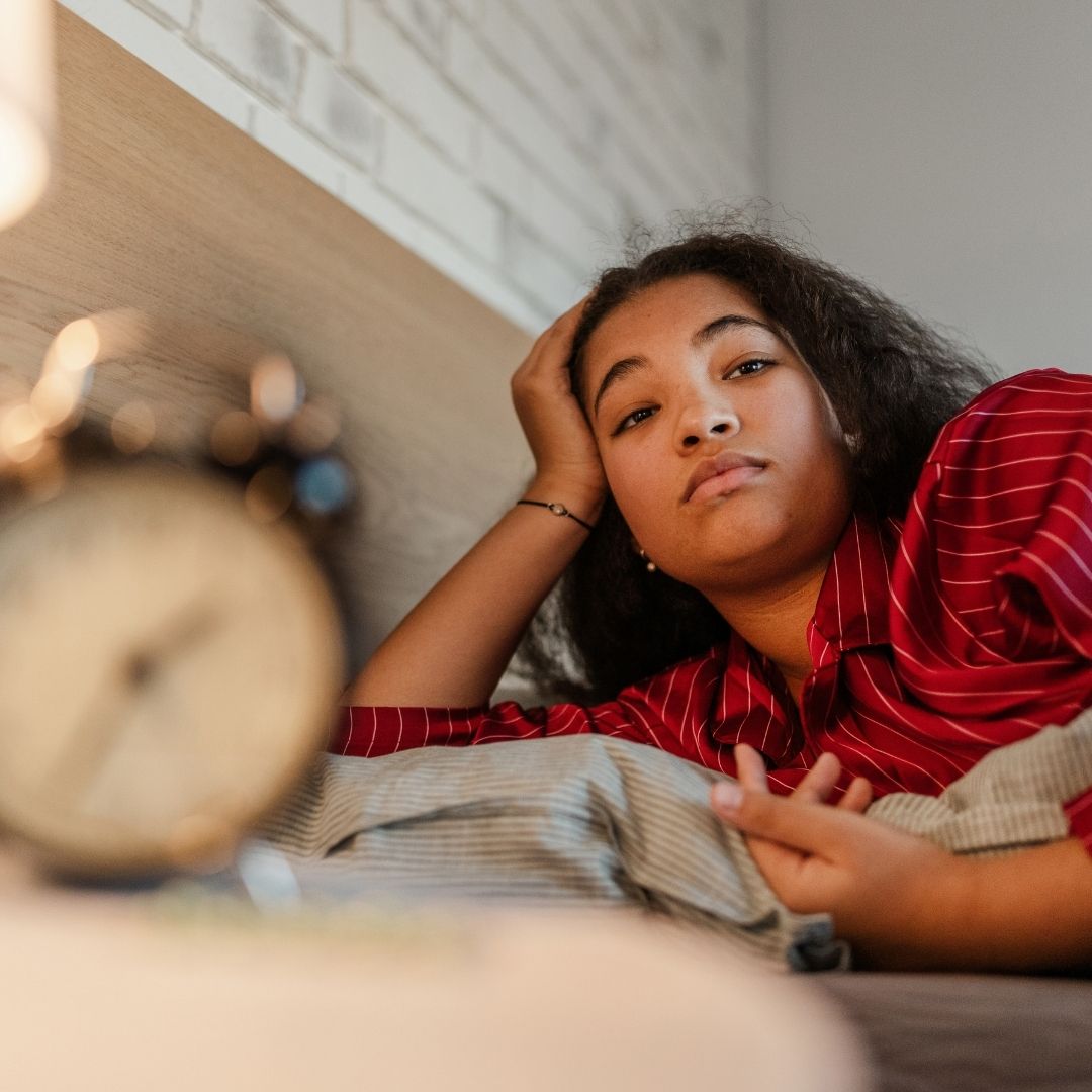 Woman lying awake feeling tired after disrupted sleep, representing sleep apnoea symptoms associated with PMOS.